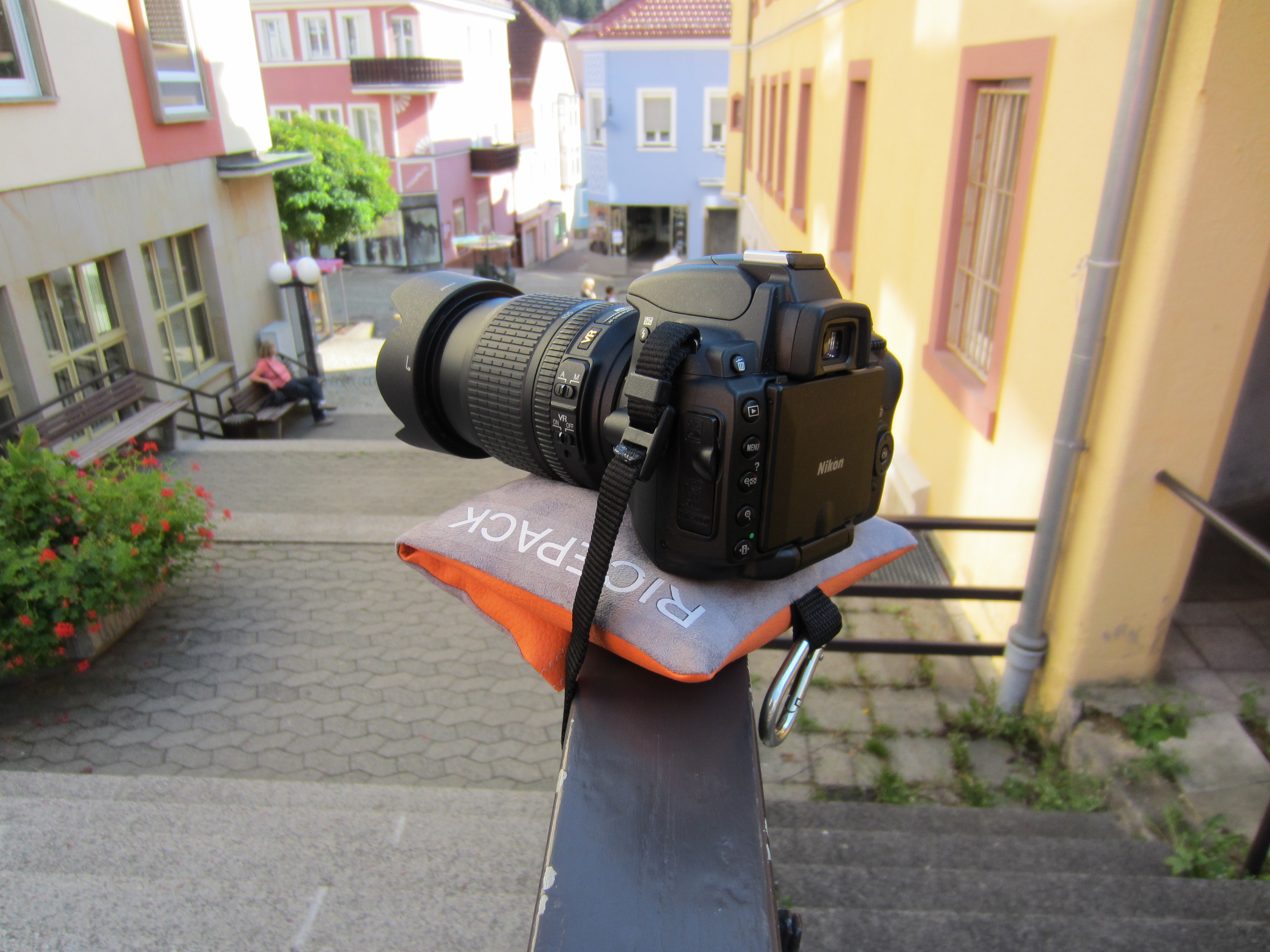 Kamera mit Teleobjektiv auf dem RiceQ Bohnensack Traveller auf einem Geländer in der Altstadt