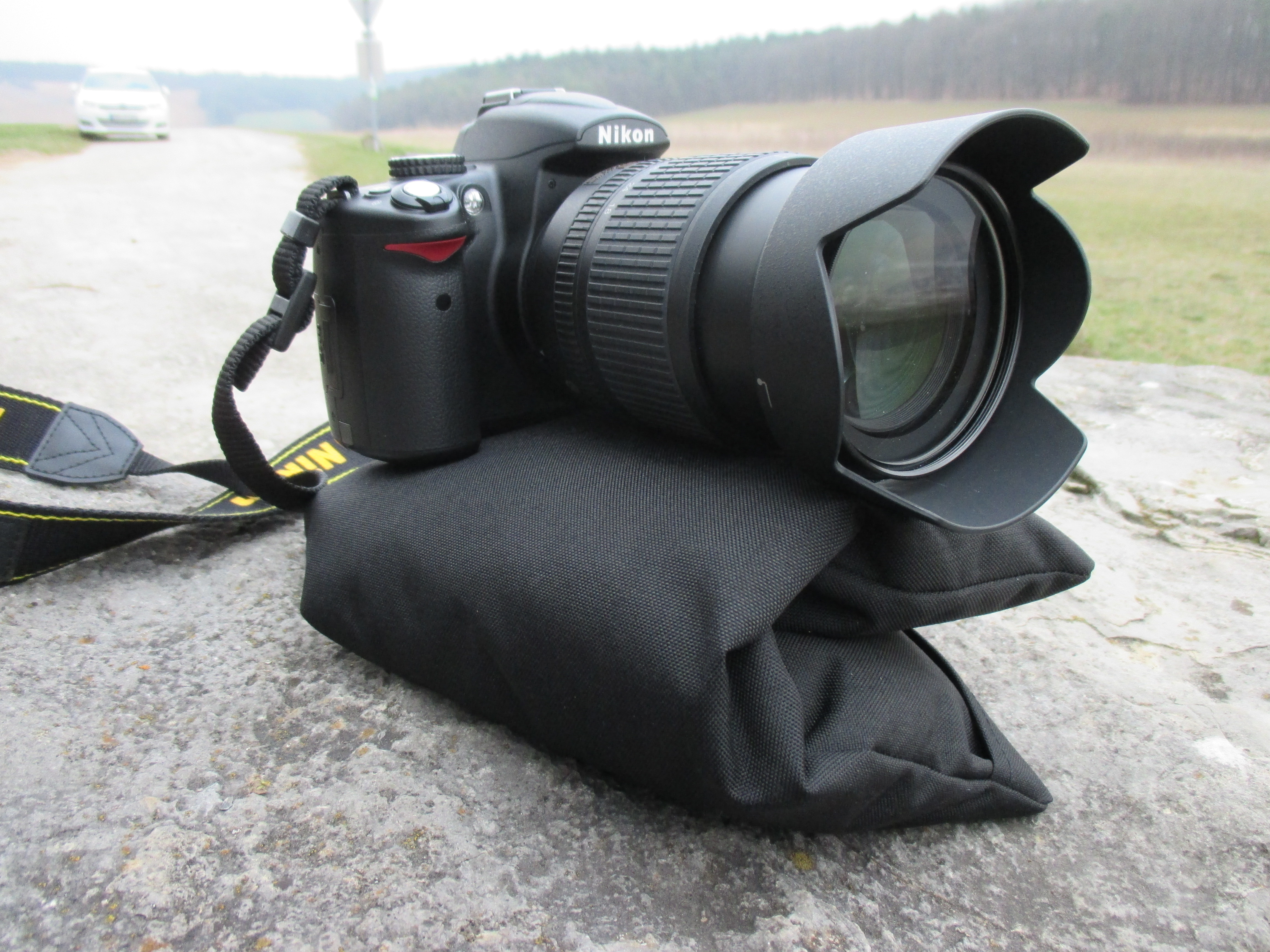 RiceQ Bohnensack Edition mit Kamera und Teleobjektiv auf einem Felsen